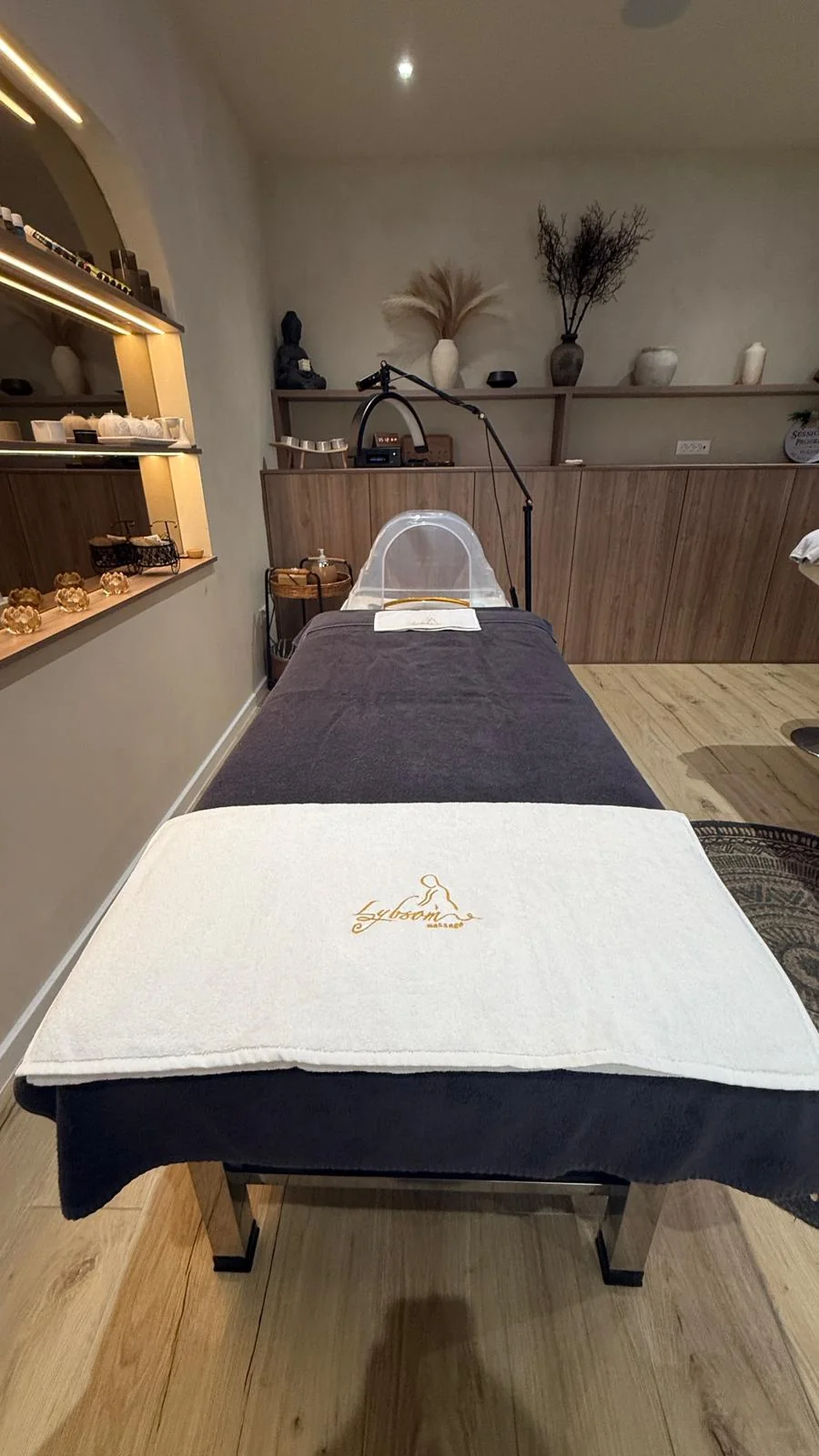 Massage bed covered with a dark cover and a white towel.