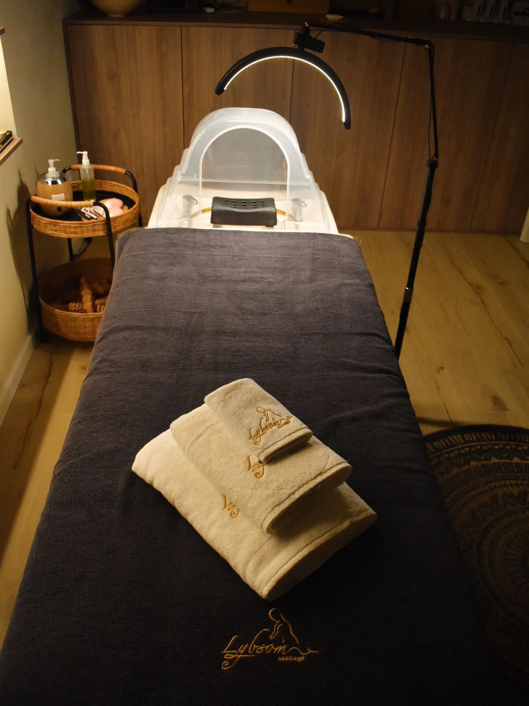 A prepared treatment table with a dark cover, folded towels and scalp-care equipment.