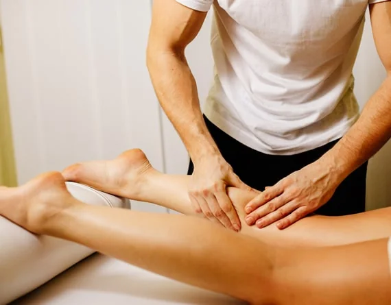 Hands massaging the thigh and leg during a body-care treatment.