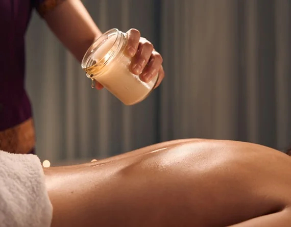 Warm oil from a massage candle being applied to the back.